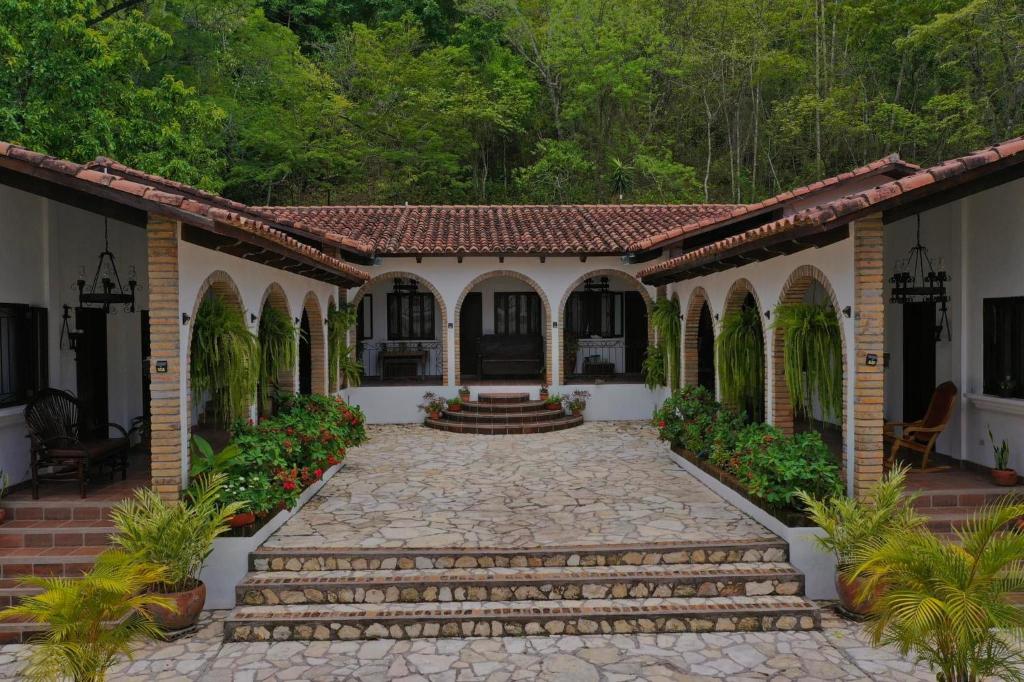 a house with a stone walkway in front at Hacienda La Esperanza in Copan Ruinas