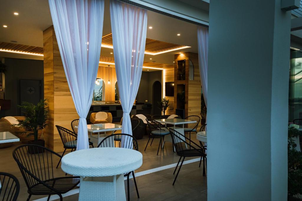 a restaurant with white curtains and tables and chairs at Residence Porto Ulisse in Parghelia