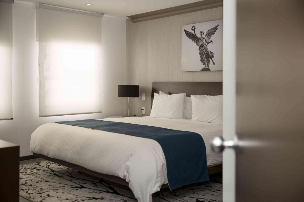a bedroom with a large bed and a window at Suites Obelisk in Mexico City