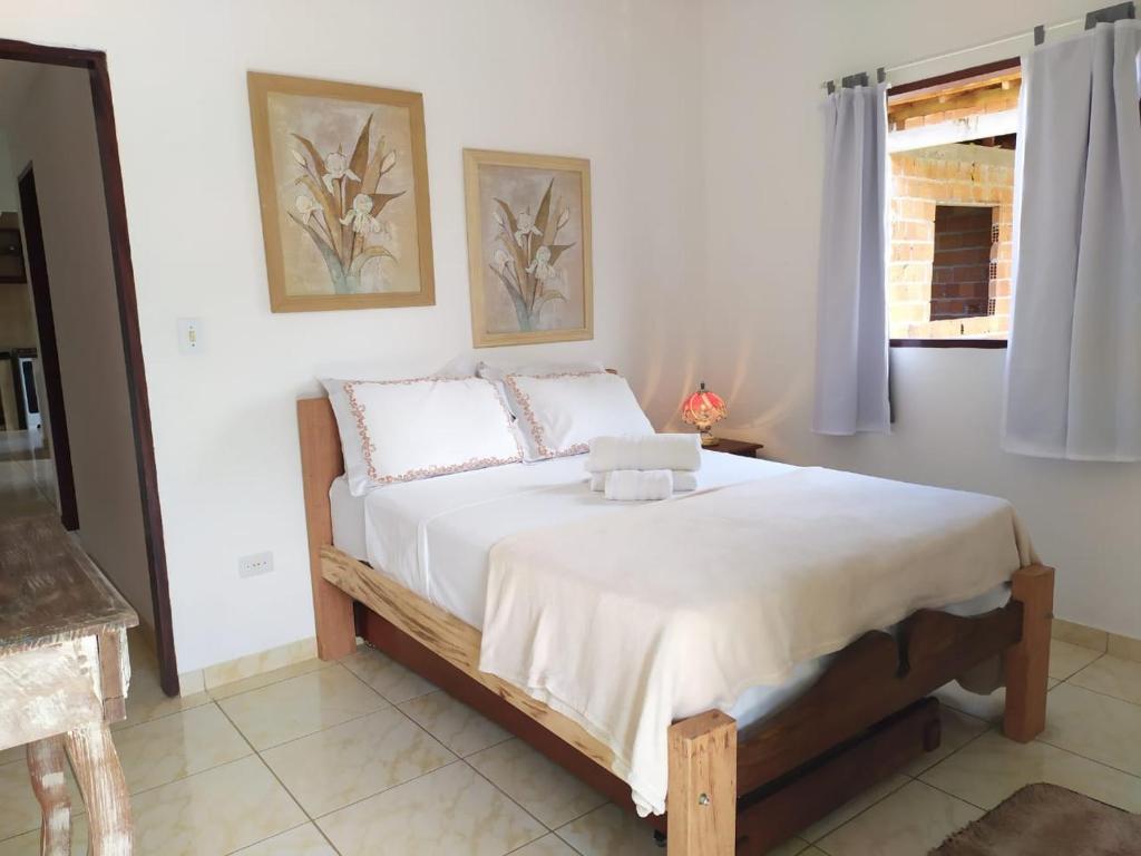 una camera da letto con un grande letto con lenzuola bianche e una finestra di Casa Próximo do Centro a Parati