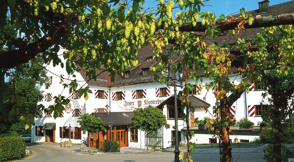 Irseer Klosterbräu في Irsee: مبنى ابيض كبير بنوافذ حمراء وشجرة