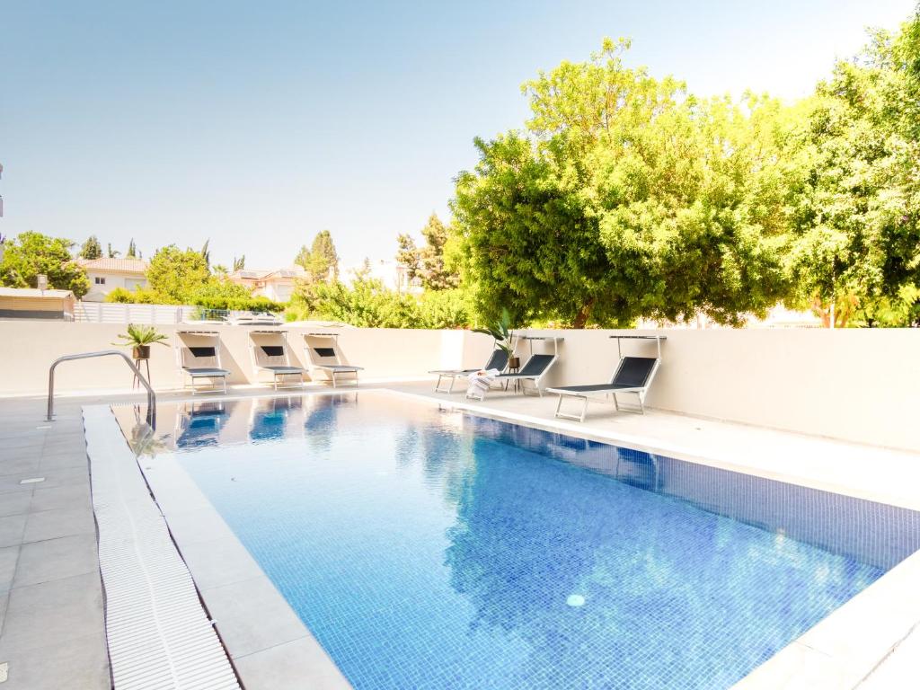 a swimming pool with lounge chairs next to a white wall at Sanders Evolution in Limassol