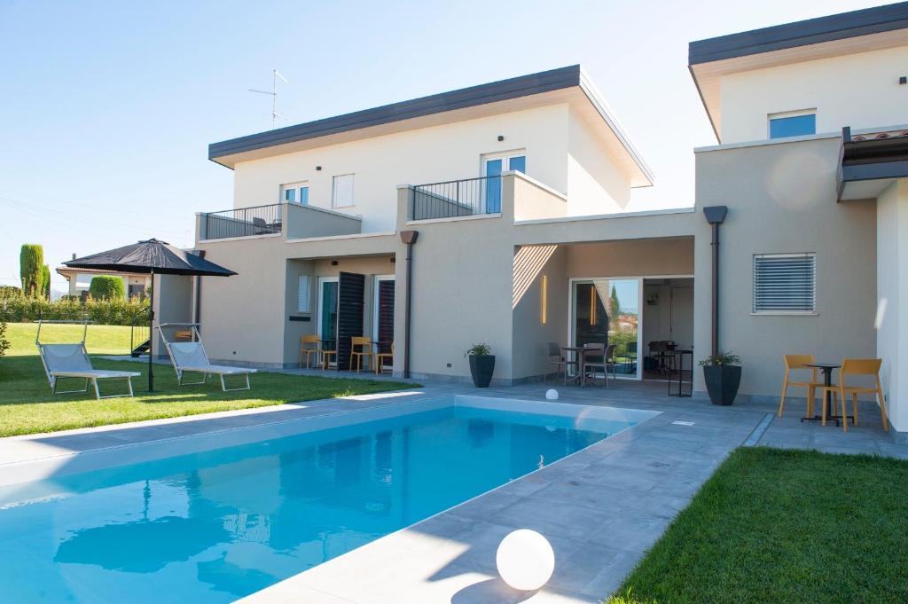 a villa with a swimming pool in front of a house at B&B Lough in Colà di Lazise