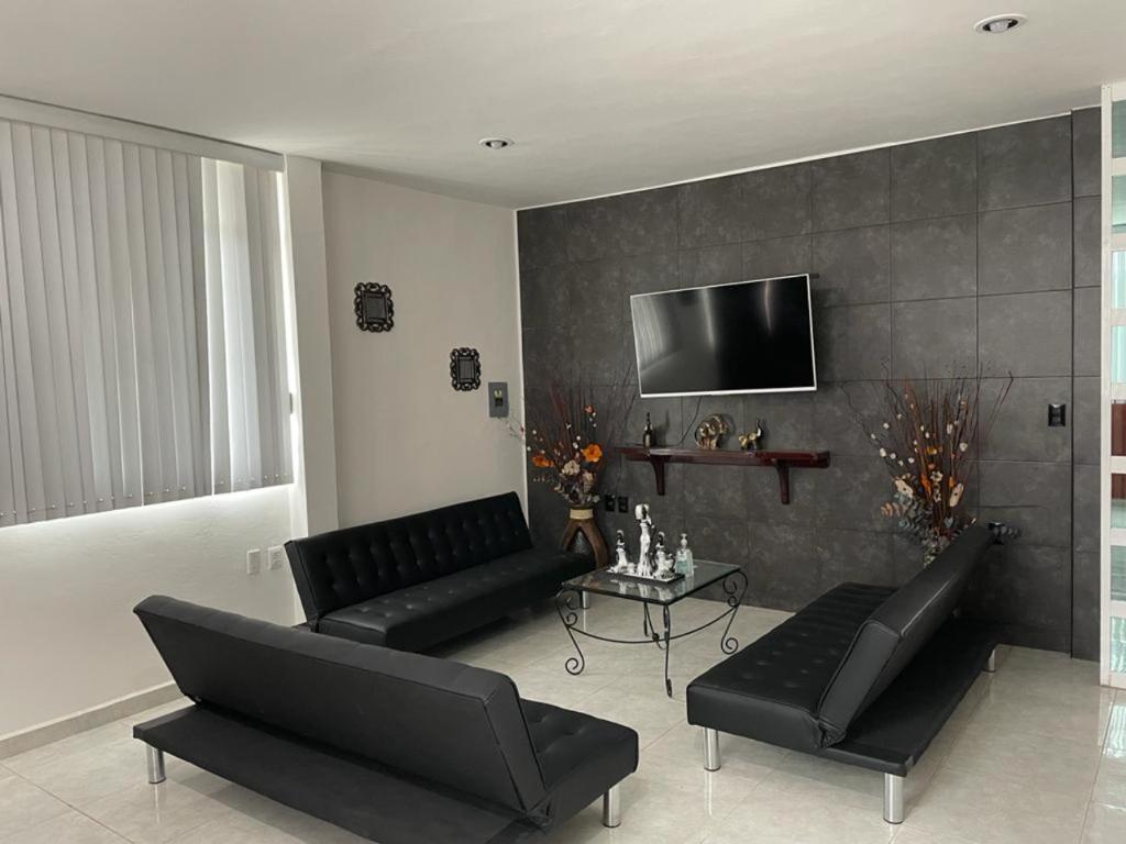 a living room with black furniture and a flat screen tv at Sensity Home Preciosa y espaciosa casa todos los servicios 5 min del CIS in Tehuacán
