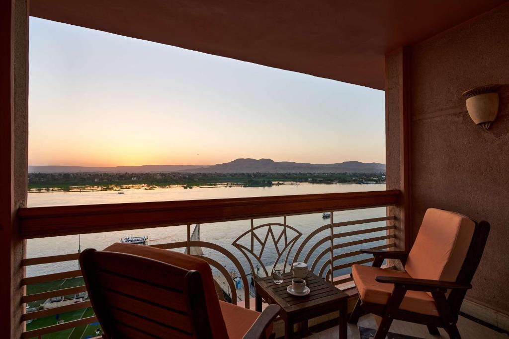 a balcony with two chairs and a view of the water at Sonesta St. George Hotel - Convention Center in Luxor
