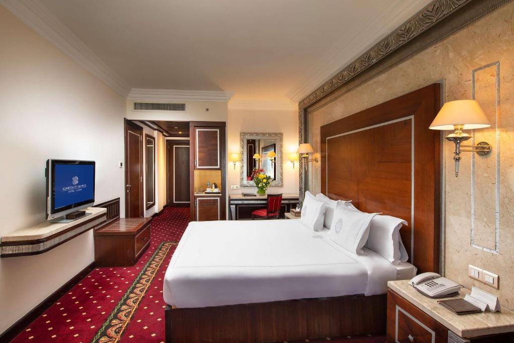 a hotel room with a large bed and a television at Sonesta St. George Hotel - Convention Center in Luxor