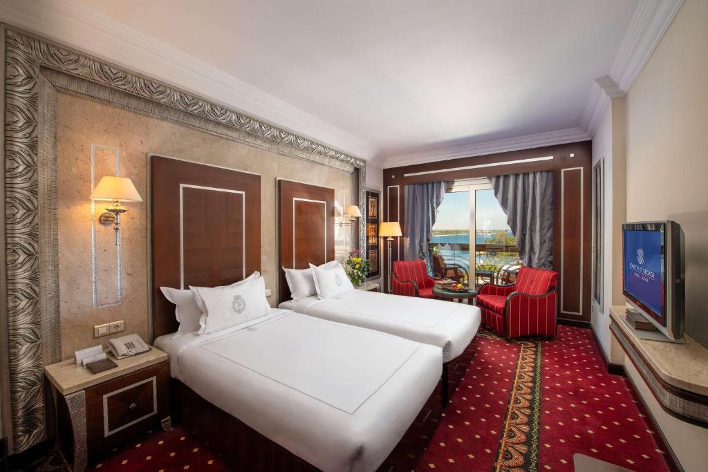 a hotel room with two beds and a flat screen tv at Sonesta St. George Hotel - Convention Center in Luxor
