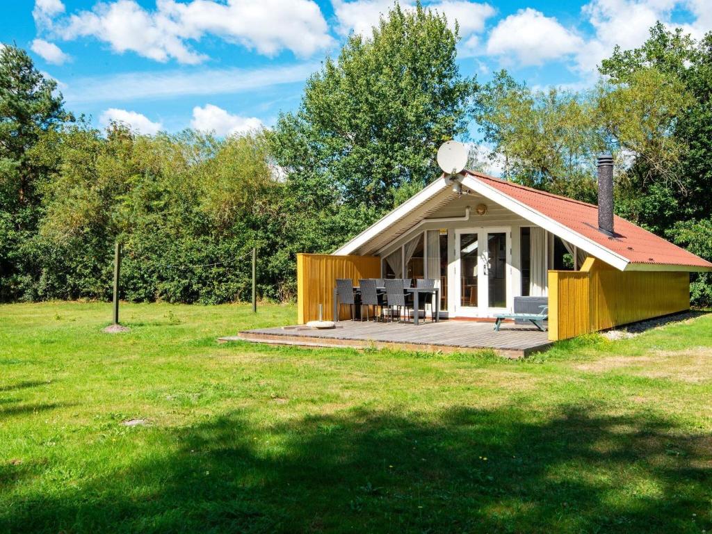 uma pequena casa com um deque num campo em 4 person holiday home in Oksb l em Øster Vrøgum