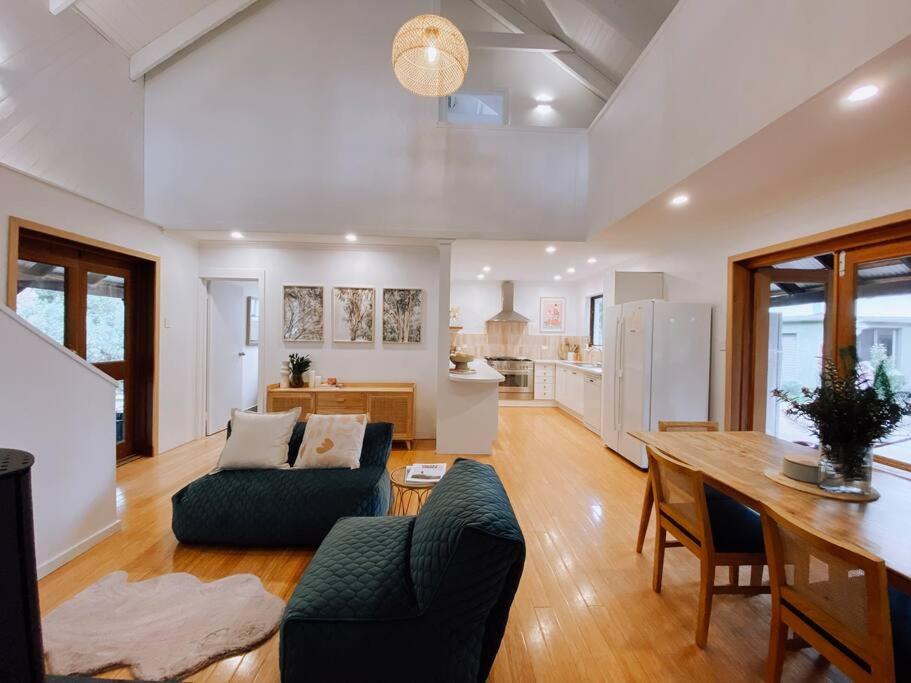 ein Wohnzimmer mit einem Sofa und einem Tisch sowie eine Küche in der Unterkunft Mika · Cabin with fireplace, walk to the beach in Dunsborough