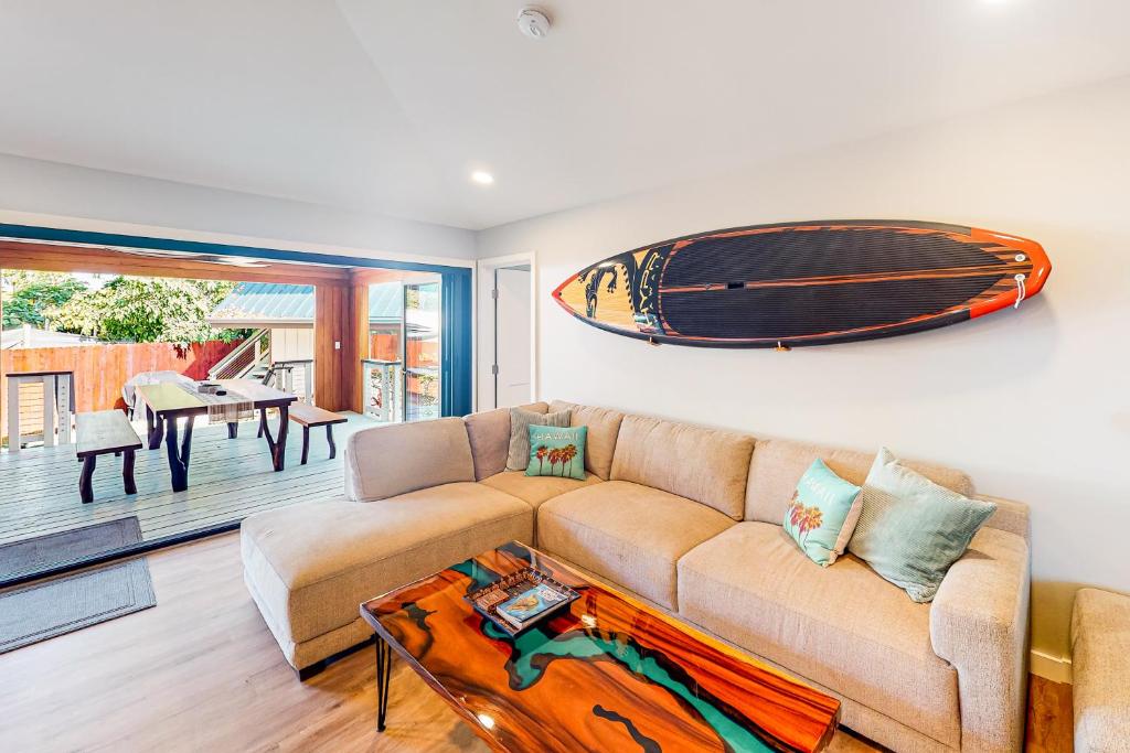 a living room with a couch and a surfboard on the wall at The Shack in Kailua-Kona