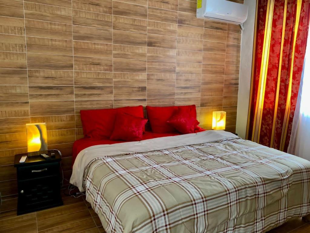 1 dormitorio con 1 cama grande con almohadas rojas en Hotel boutique CVC, en Acapulco