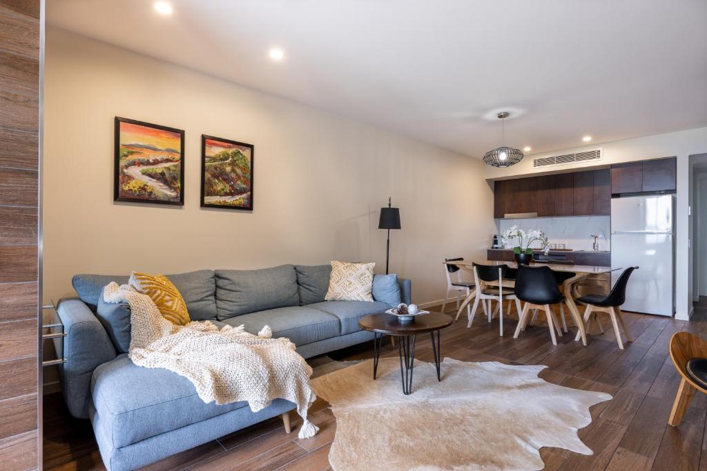 uma sala de estar com um sofá azul e uma cozinha em Luxury Hinterland Retreat - Family Suite with Hinterland and Ocean Views em Montville