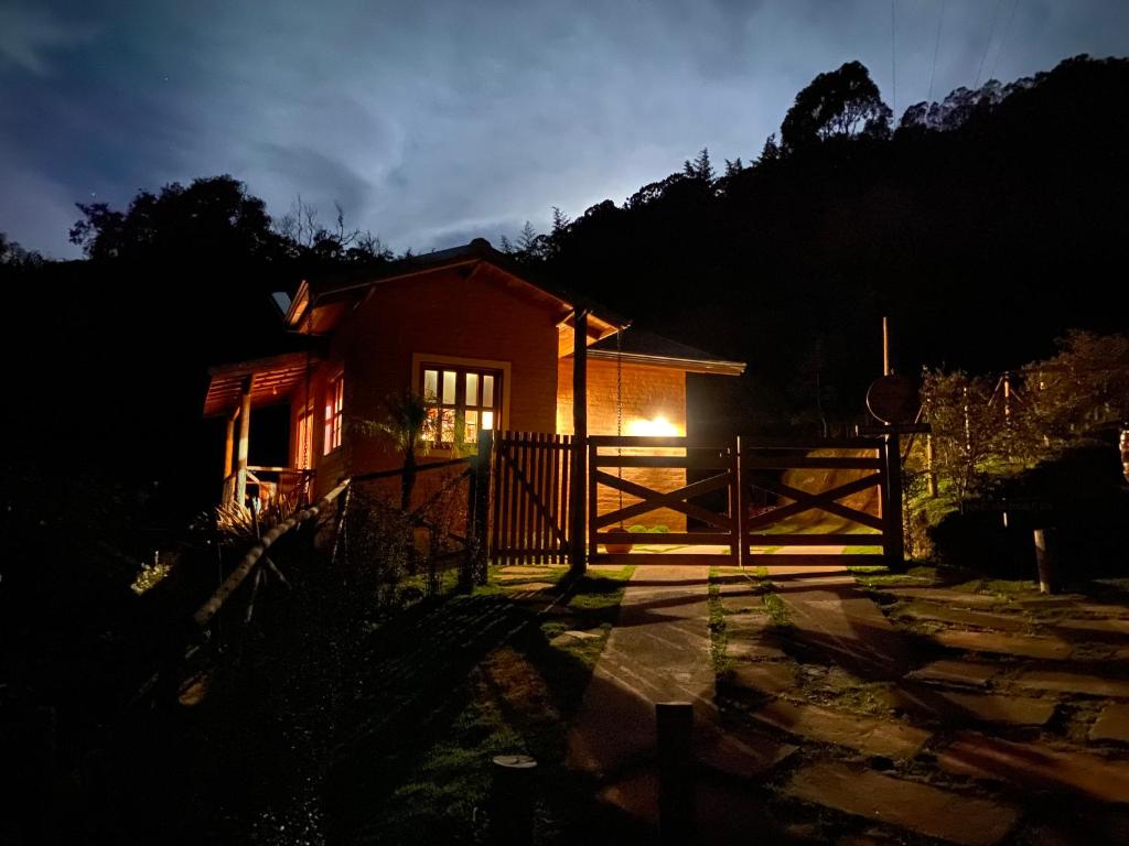 ein kleines rotes Haus mit einem Tor und einem Zaun in der Unterkunft Chalé Som da 7 Quedas Apenas 1,8km do Centro de Gonçalves MG in Gonçalves