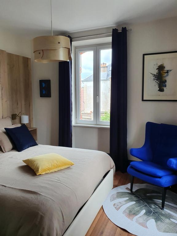 een slaapkamer met een bed en een blauwe stoel bij villa l'Ambroisine in Lure