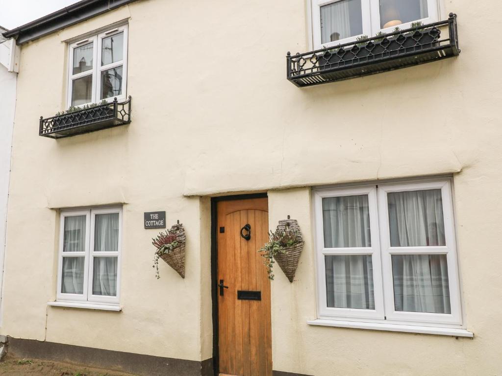 a white house with a wooden door and windows at Beach Retreat in Bideford