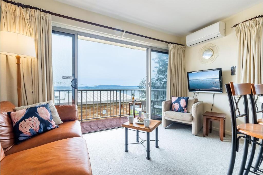 a living room with a couch and a large window at Sunnie Belle, 2,3 Victoria Parade - Unit with water views and air conditioning in Nelson Bay