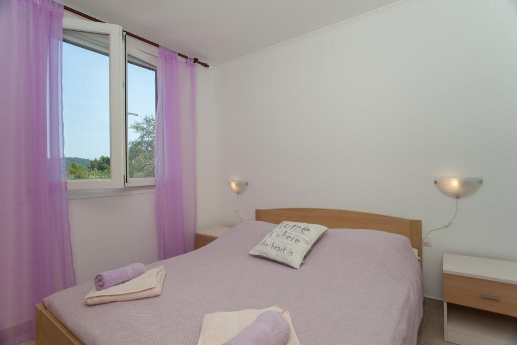 a bedroom with a bed with purple curtains and a window at Seaside holiday house Cove Gabrica, Korcula - 17195 in Vela Luka