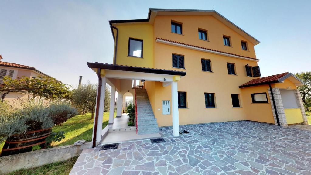 une grande maison jaune avec une allée. dans l'établissement Apartments with a parking space Vilanija, Umag - 17240, à Umag