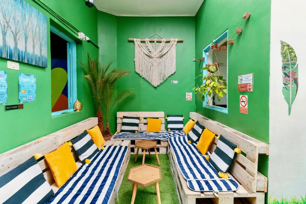 a table and chairs in a room with a green wall at The Secret Garden Hostel in Lima