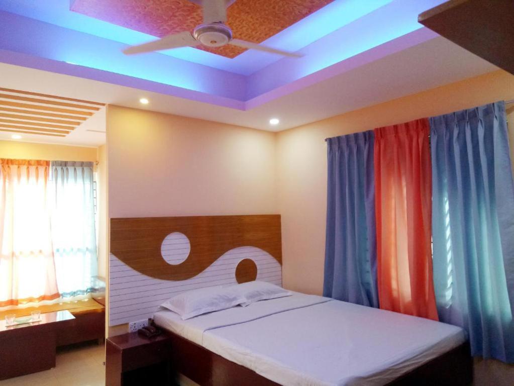 a bedroom with a bed with colorful curtains and a ceiling at Shopnonir Hotel & Restaurant in Chittagong
