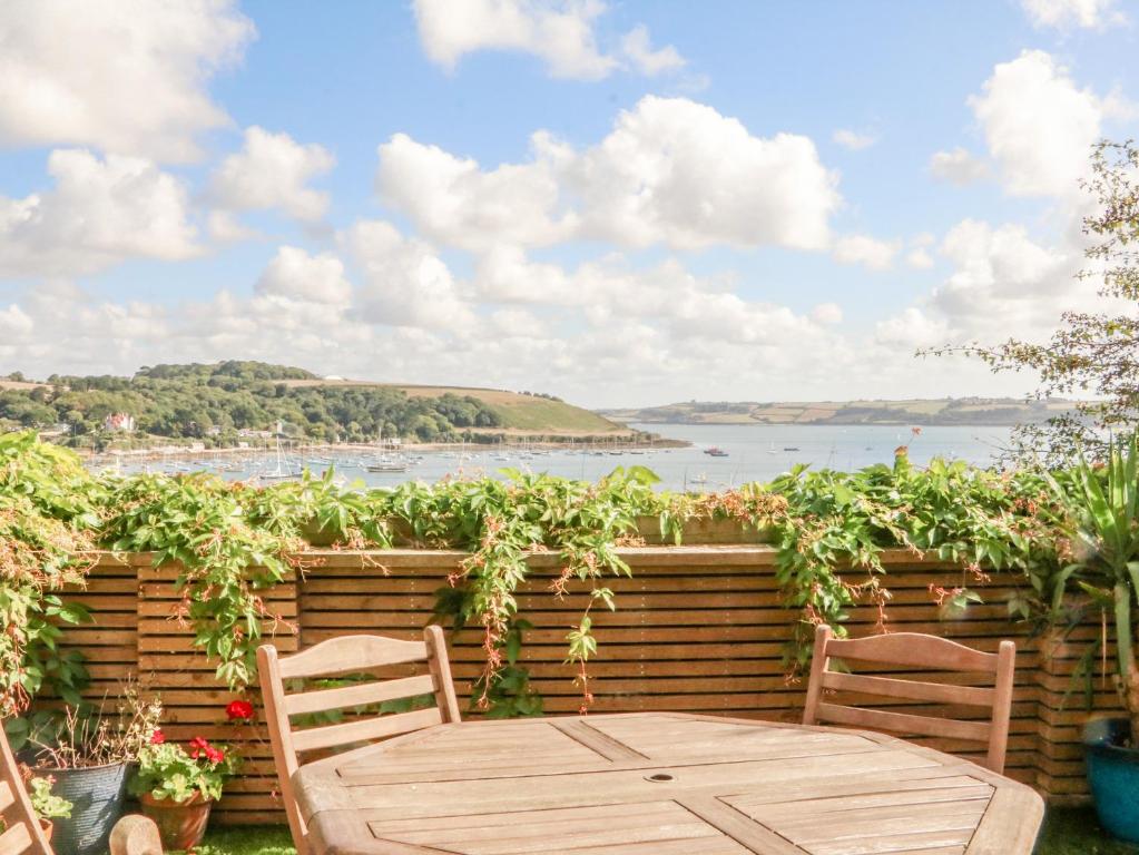a wooden table and chairs on a patio with a view of the water at Through The Porthole in Falmouth