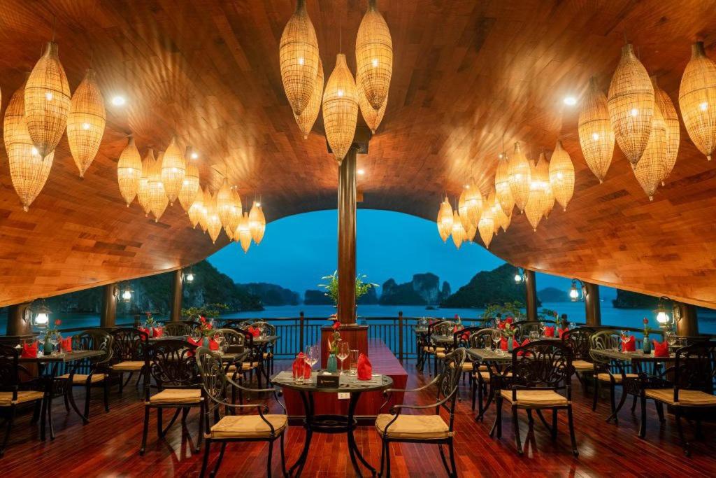 a restaurant with tables and chairs and chandeliers at Sena Cruises - Wonder On Lan Ha Bay in Ha Long
