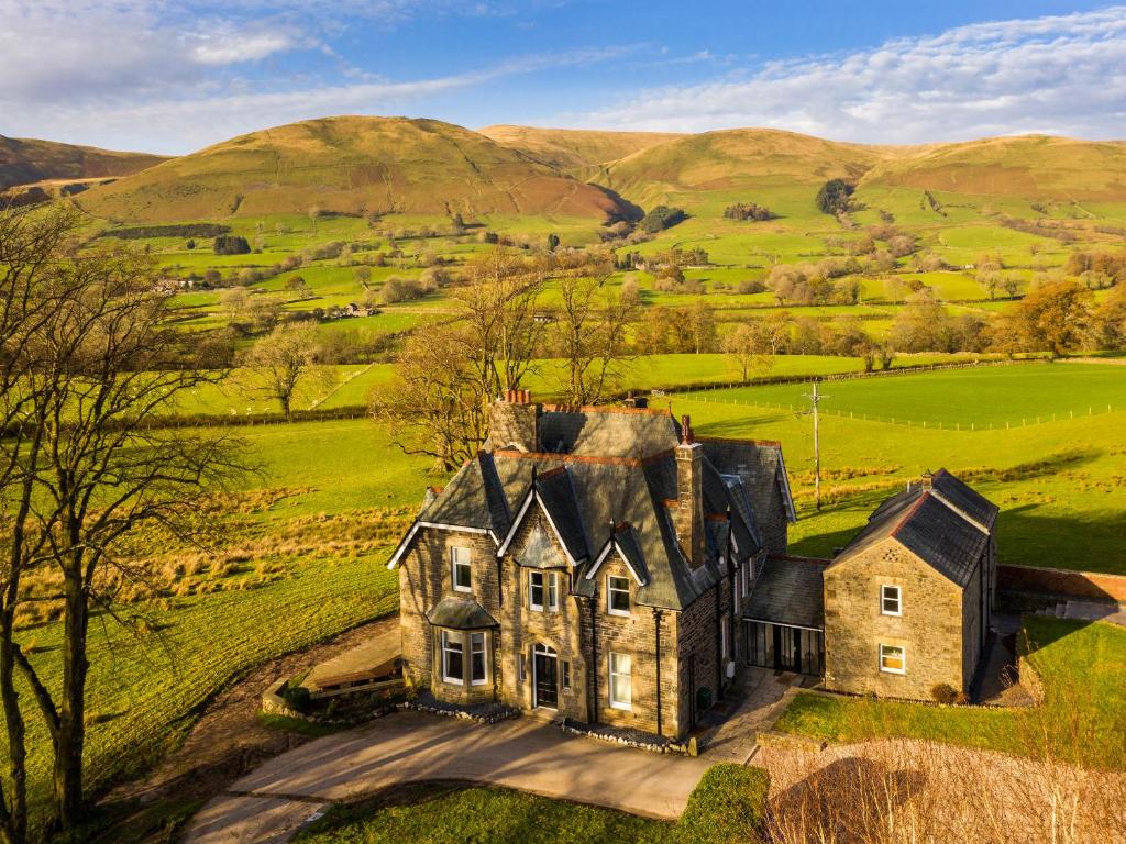 an old house in a field with hills in the background at Oakdene Country House in Sedbergh