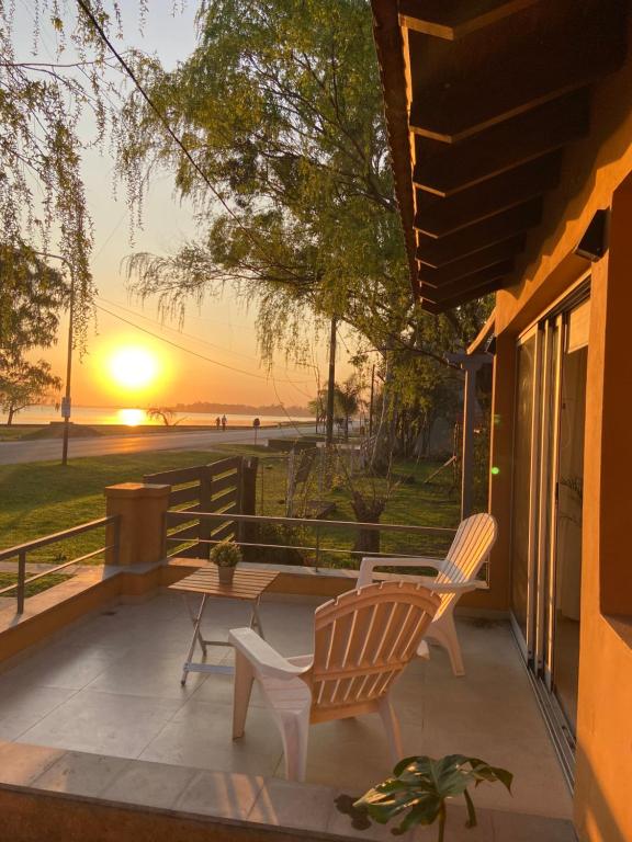 eine Terrasse mit 2 Stühlen, einem Tisch und einem Sonnenuntergang in der Unterkunft Casa Chalet "La Roja" -vista a la laguna!!!- in Chascomús