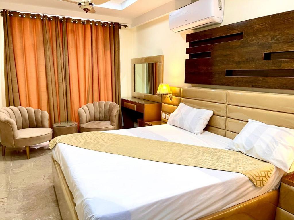 pokój hotelowy z łóżkiem i 2 krzesłami w obiekcie Hotel H6 w mieście Rawalpindi