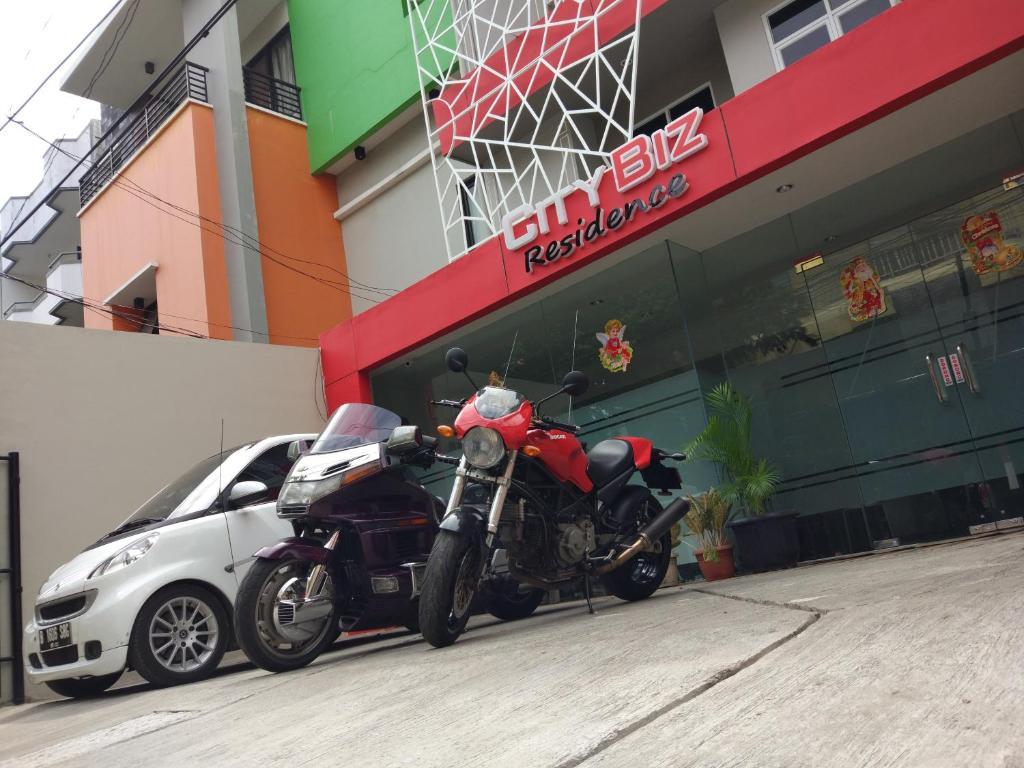 a motorcycle and a car parked in front of a building at City Biz Residence in Jakarta