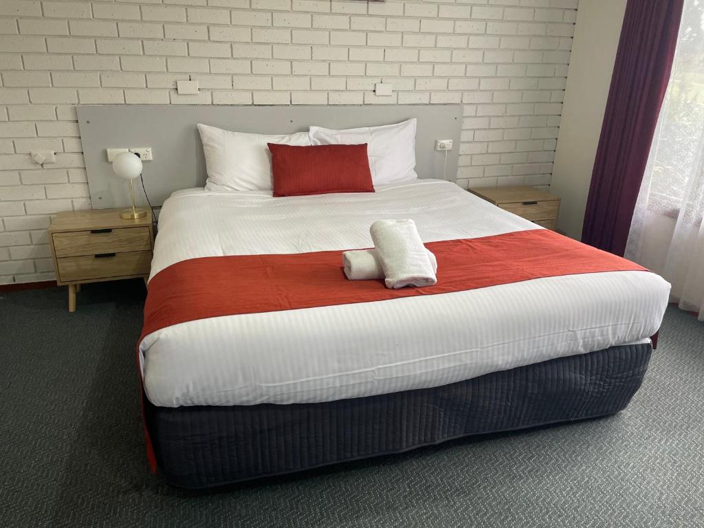 a bedroom with a large bed with a red and white blanket at Warragul Views Motor Inn in Warragul