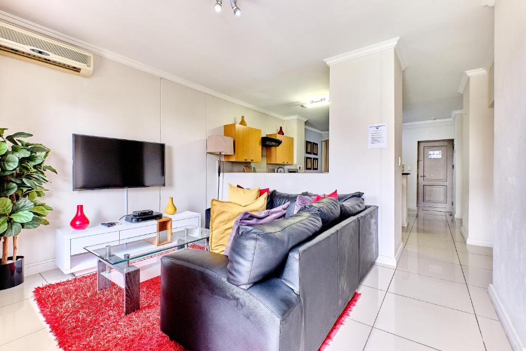 uma sala de estar com um sofá e uma televisão em Westpoint Glammys Suites em Joanesburgo