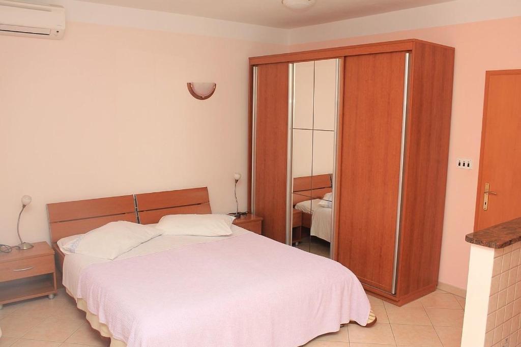 Schlafzimmer mit einem weißen Bett und einem Holzschrank in der Unterkunft Apartments by the sea Moscenicka Draga, Opatija - 17381 in Mošćenička Draga