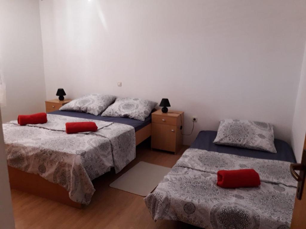 2 łóżka z czerwonymi poduszkami w pokoju w obiekcie Apartments with a parking space Zadar - 17409 w mieście Zadar