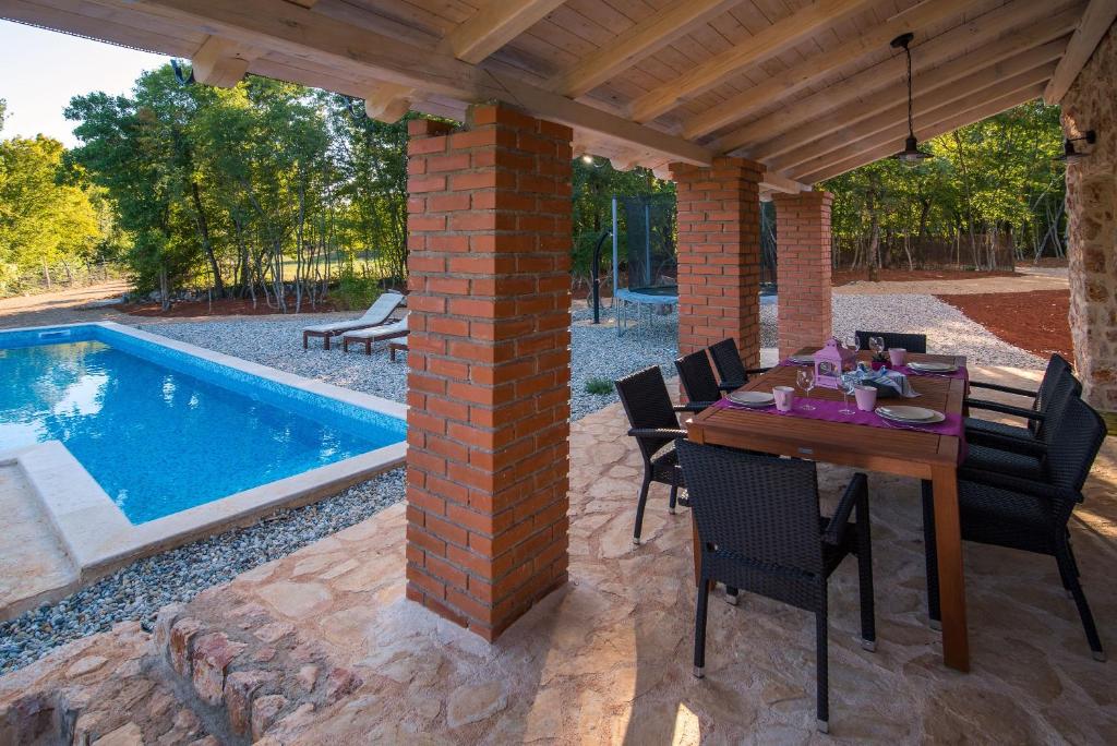 patio ze stołem i krzesłami oraz basenem w obiekcie Luxury villa with a swimming pool Risika, Krk - 17410 w mieście Vrbnik