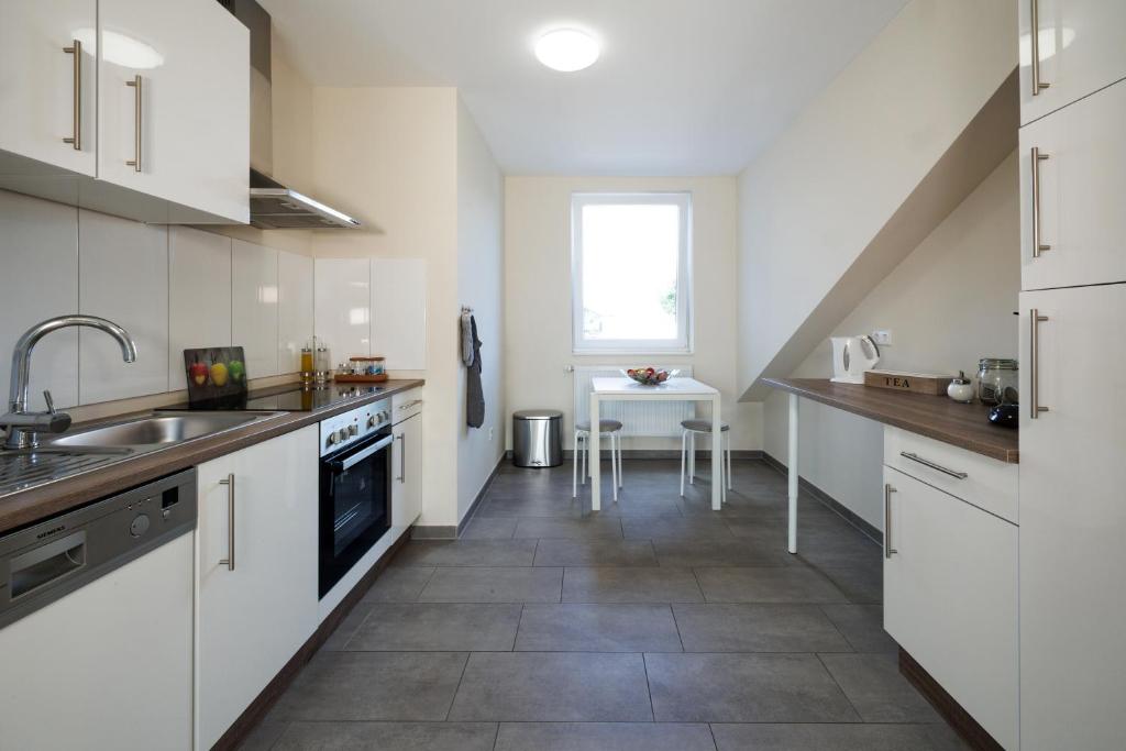 a kitchen with white cabinets and a sink and a table at Hotel Jellentrup in Münster