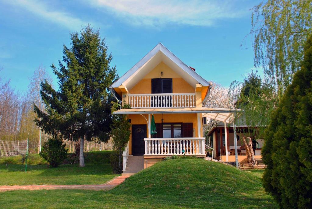 una pequeña casa amarilla con balcón en un patio en Family friendly house with a swimming pool Nova Kapela, Slavonija - 17313, en Nova Kapela