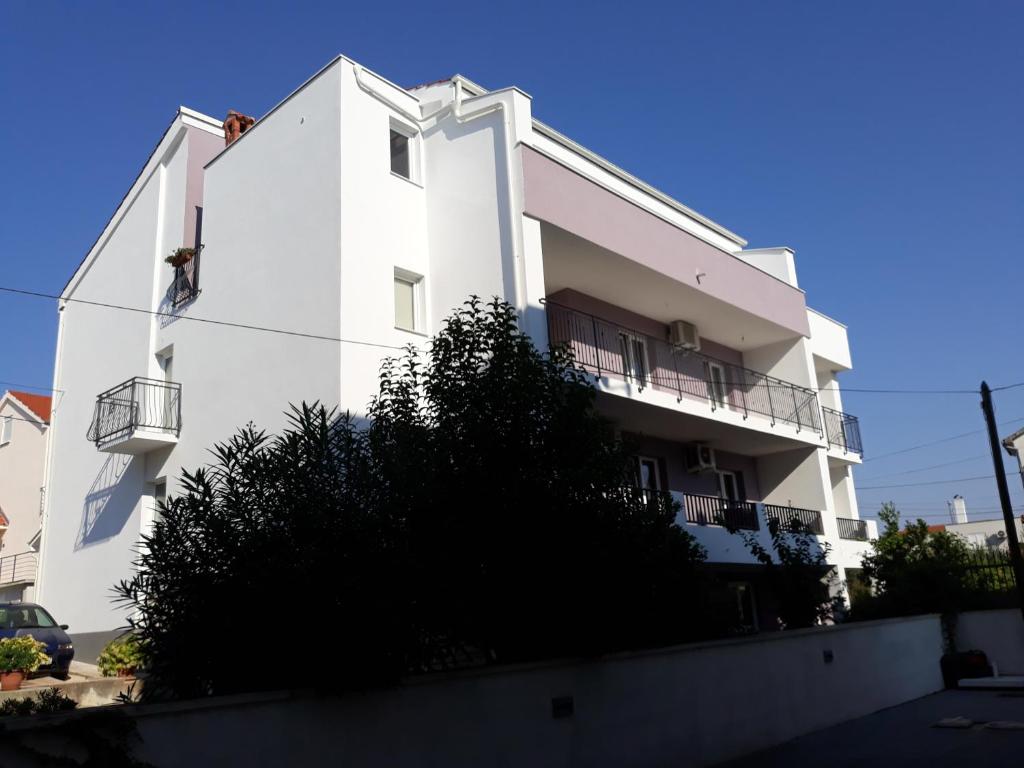 um edifício branco com um homem a trabalhar nele em Apartments by the sea Zadar - Diklo, Zadar - 17199 em Zadar