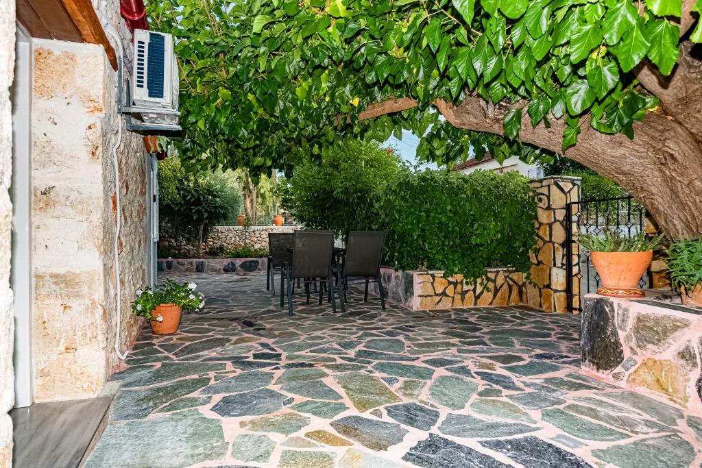 un patio de piedra con sillas bajo un árbol en Helen's House, en Arménoi