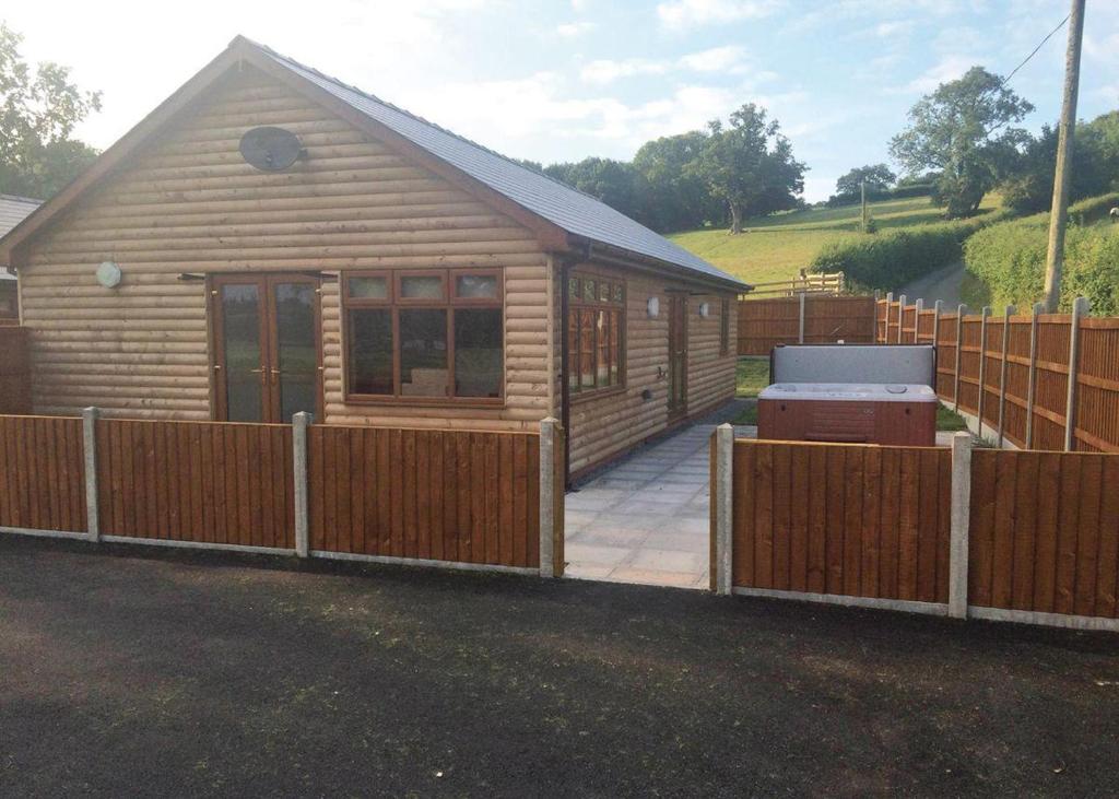 a log cabin with a fence around it at Heart Of Wales Lodges in Penybont