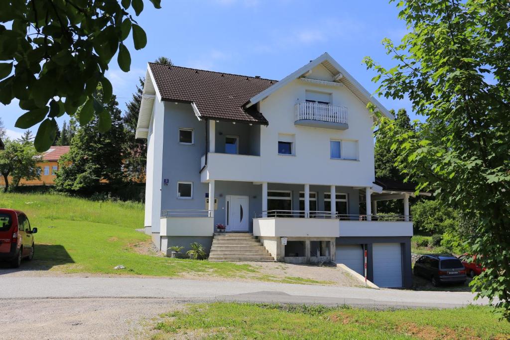 uma grande casa branca com um carro estacionado em frente em Apartments for families with children Slunj, Plitvice - 17416 em Slunj