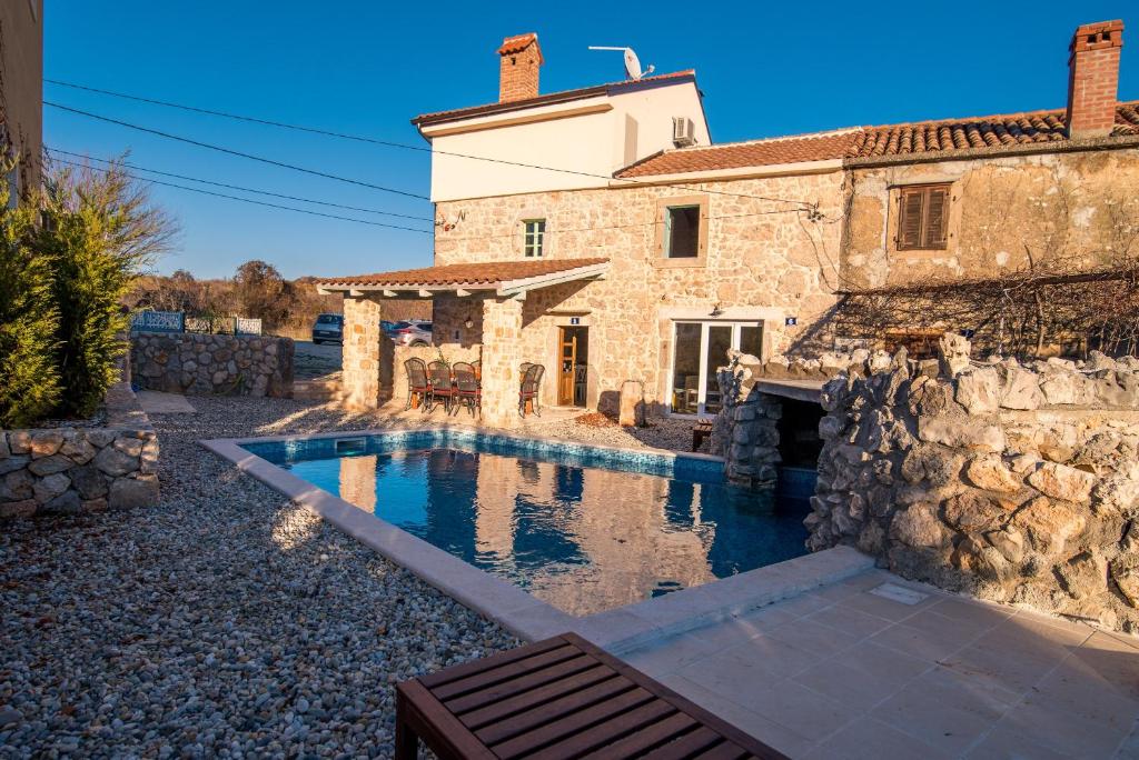 a stone house with a swimming pool in front of it at Luxury villa with a swimming pool Garica, Krk - 17469 in Risika