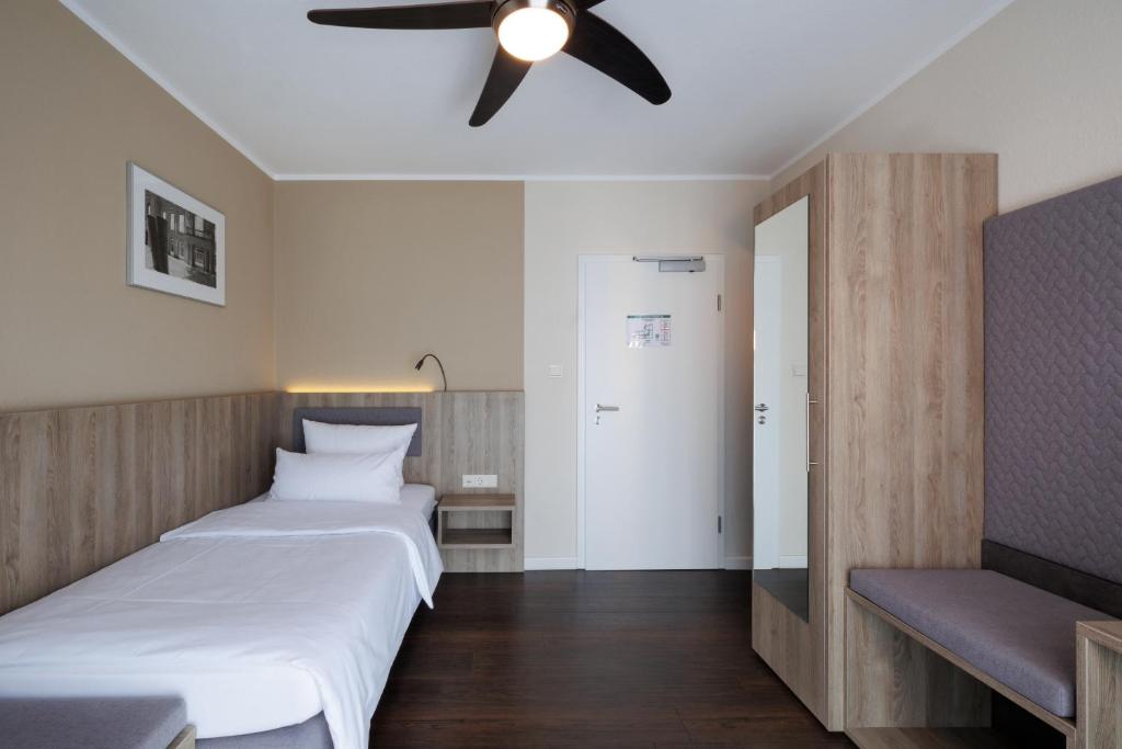 a bedroom with two beds and a ceiling fan at Hotel Jellentrup in Münster