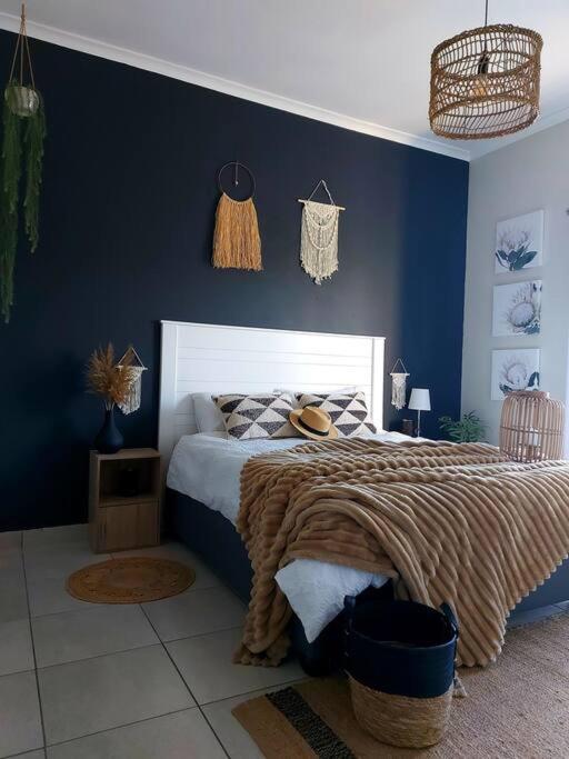a bedroom with a bed with a blue wall at Flower Route House in Langebaan