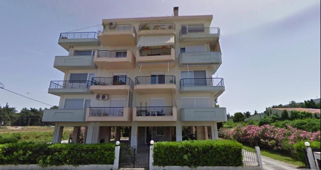 a tall white building with balconies and bushes at Hidden Gem Apartment in Neoi Epivates