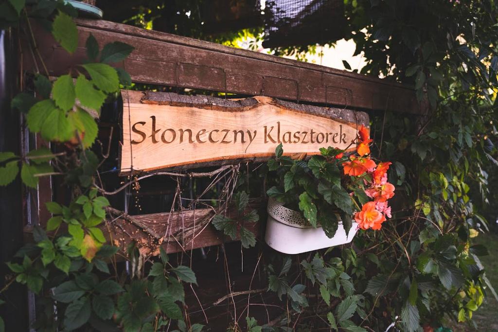 a sign on a wall with flowers in a pot at Słoneczny Klasztorek in Gardeja