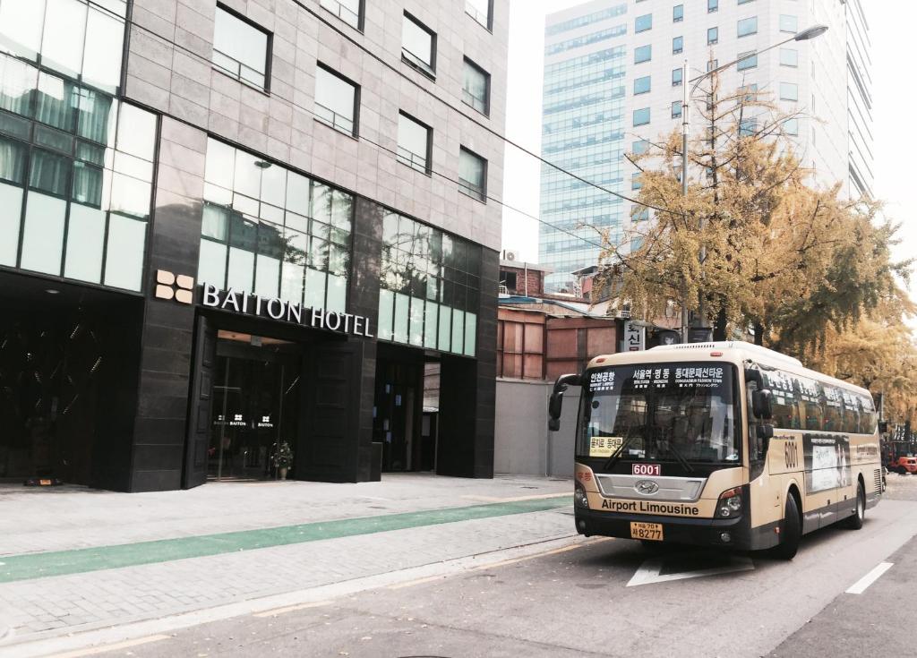 un autobus è parcheggiato di fronte a un edificio di Baiton Seoul Dongdaemun a Seul