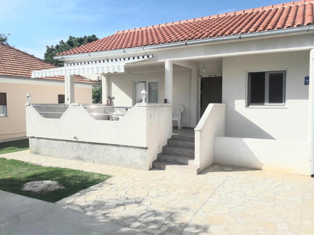 een wit huis met een veranda en een trap bij Apartments by the sea Vrsi - Mulo, Zadar - 17066 in Vrsi