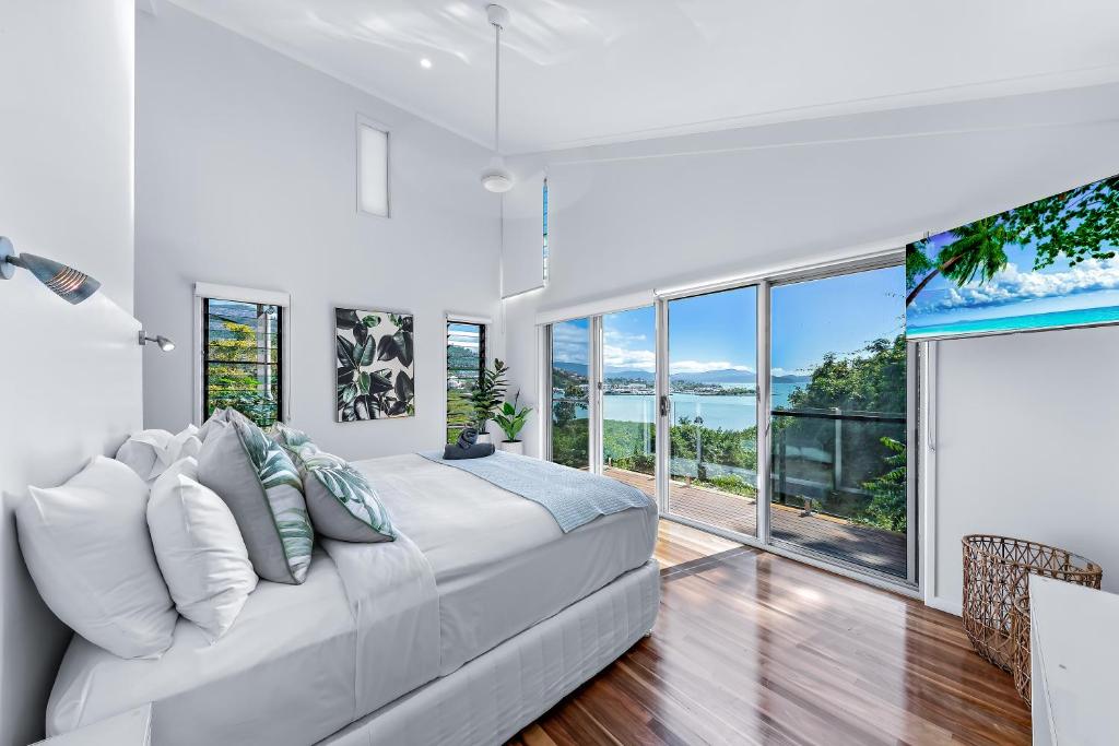 a white bedroom with a large bed and large windows at MANDALAY ESCAPE, SECLUSION & SERENITY WITH A POOL in Airlie Beach