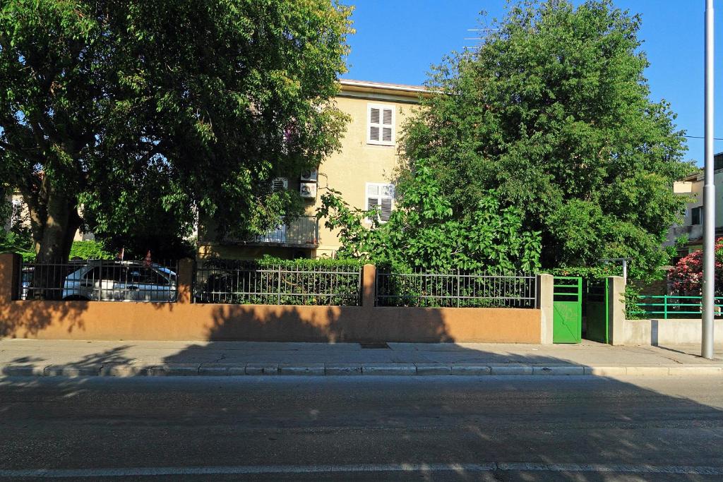 una valla frente a un edificio con árboles en Apartment Split 17386a en Split